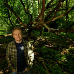 Zdjęcie przedstawia Piotra Horzelę na tle lasu