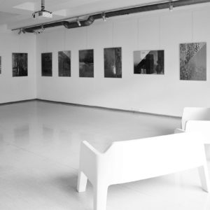 Czarno-biala fotografia przedstawiająca wnętrze galerii. Na białych ścianach znajdują się czarnobiałe, abstrakcyjne grafiki Ryszarda Pielesza.