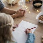 Zdjęcie przedstawia widok na dziewczynkę piszącą list do Świętego Mikołaja.
