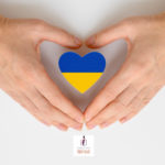 Zdjęcie przedstawiające dwie dłonie ułożone na kształt serca. W środku, pomiędzy nimi, znajduje się klocek w kształcie serca w barwach niebiesko-żółtej flagi ukraińskiej