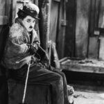 Siedzący Charlie Chaplin na drewnianej ławce