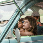 Zdjęcie przedstawia dzieci siedzące w samochodzie