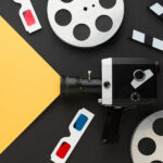 grafika z żółtym tłem, po prawej stronie czarne tło na której rozmieszczone elementy kinowe okulary 3d i kamera