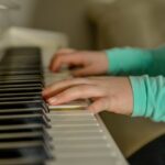 na zdjęciu ręce dziecka grające na fortepianie