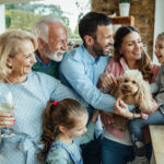 Wesoła wielopokoleniowa rodzina z psem bawiącym się wspólnie spędzającym czas w domu